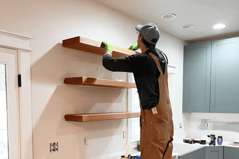 Custom Shelves Install Worker installing wooden shelves on a white wall in a modern kitchen.