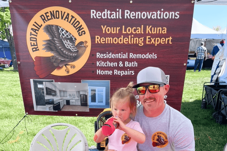 Redtail Renovations Booth Man and child at Redtail Renovations outdoor event with banner in background.