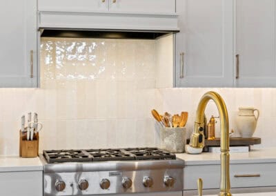 Bright modern kitchen with white cabinets, gold fixtures, and a marble countertop.