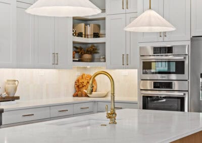 Bright modern kitchen with white cabinets, gold fixtures, and a large island.