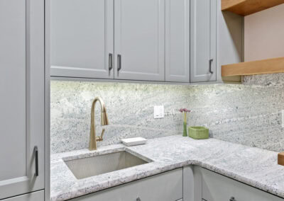 Contemporary kitchen with light gray cabinets, granite countertops, and wooden shelves.
