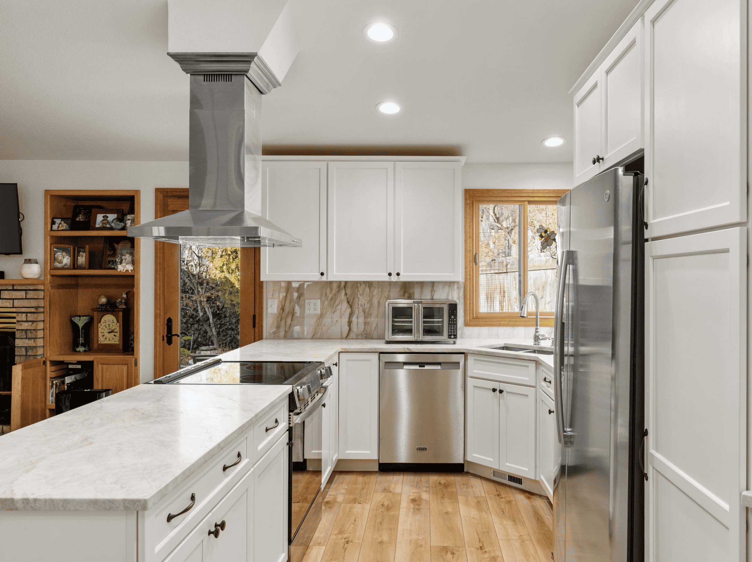Modern Kitchen Design Bright modern kitchen with white cabinets, stainless steel appliances, and wooden flooring.