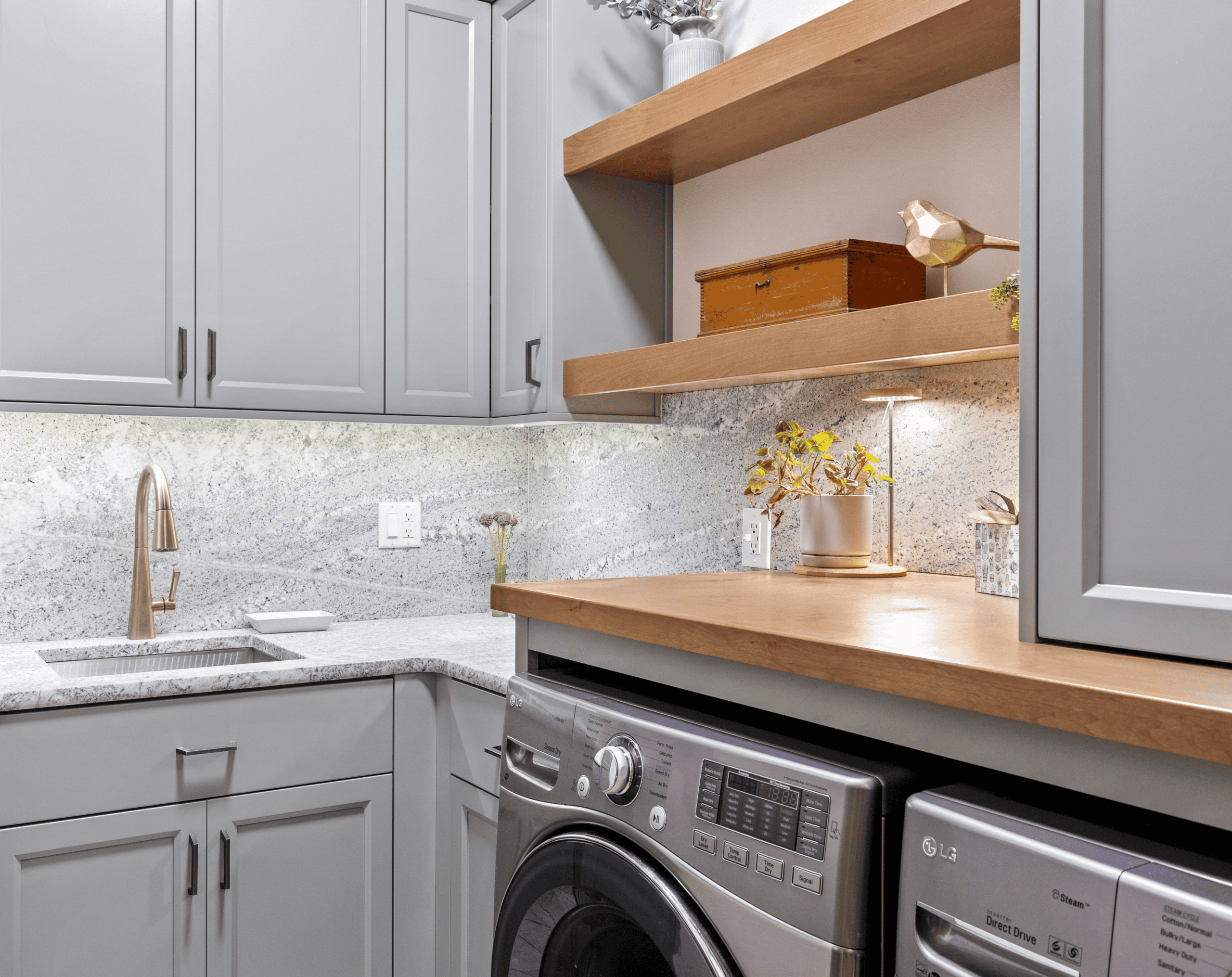Contemporary laundry room with gray cabinets, wooden shelves, and a washing machine.