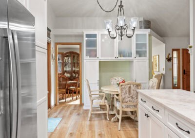Bright kitchen with white cabinets, wooden dining table, and chandelier lighting.