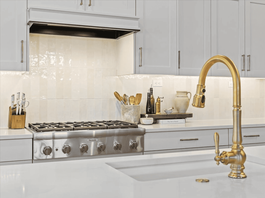Modern Kitchen Design Contemporary kitchen with white cabinets, gold faucet, and stainless steel stove.
