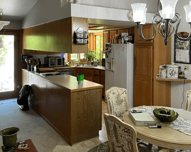 Example Co Kitchen Cozy kitchen with wooden cabinets, white appliances, and a dining area with floral chairs.