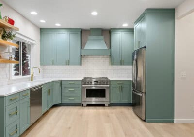 Contemporary kitchen with teal cabinets, stainless steel appliances, and white backsplash.