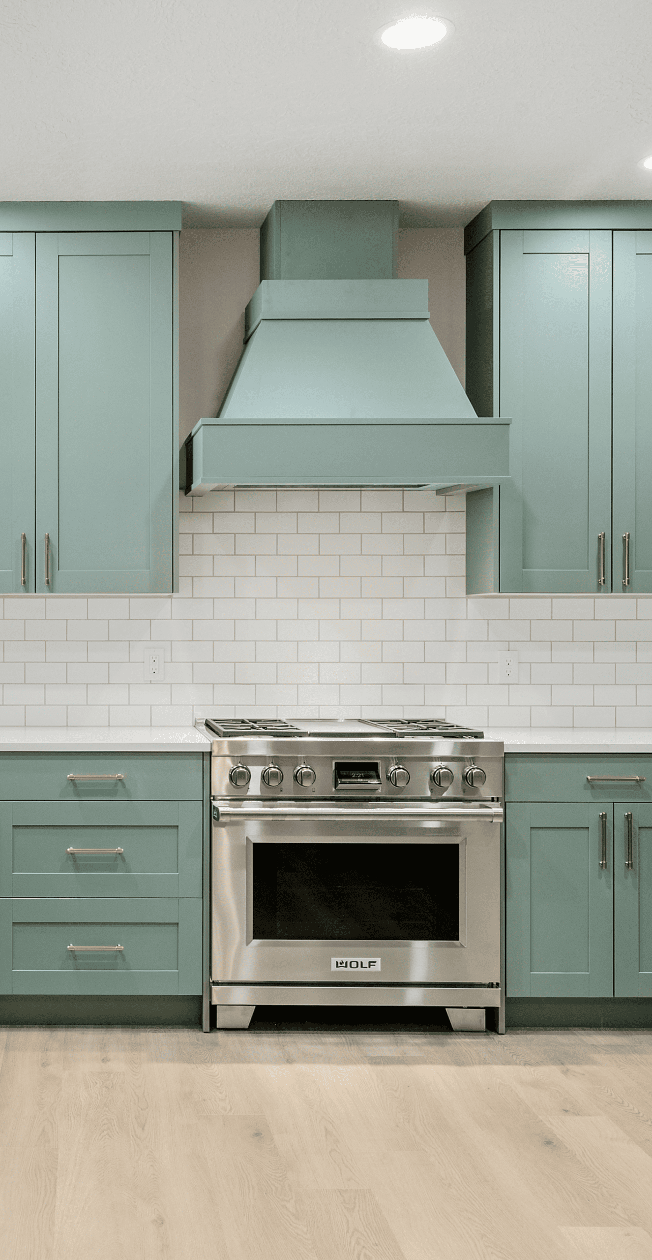 Modern Kitchen Design Contemporary kitchen with mint green cabinets and stainless steel stove and range hood.