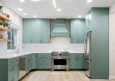 Spacious modern kitchen with teal cabinets, stainless steel appliances, and wooden flooring.