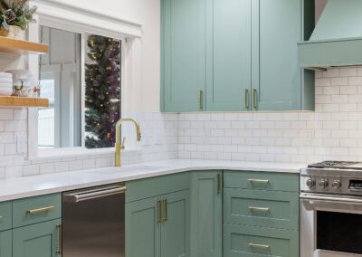 Contemporary kitchen with green cabinets, white subway tile backsplash, and stainless steel stove.