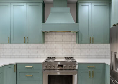 Contemporary kitchen with teal cabinets, white subway tile backsplash, and stainless steel stove.