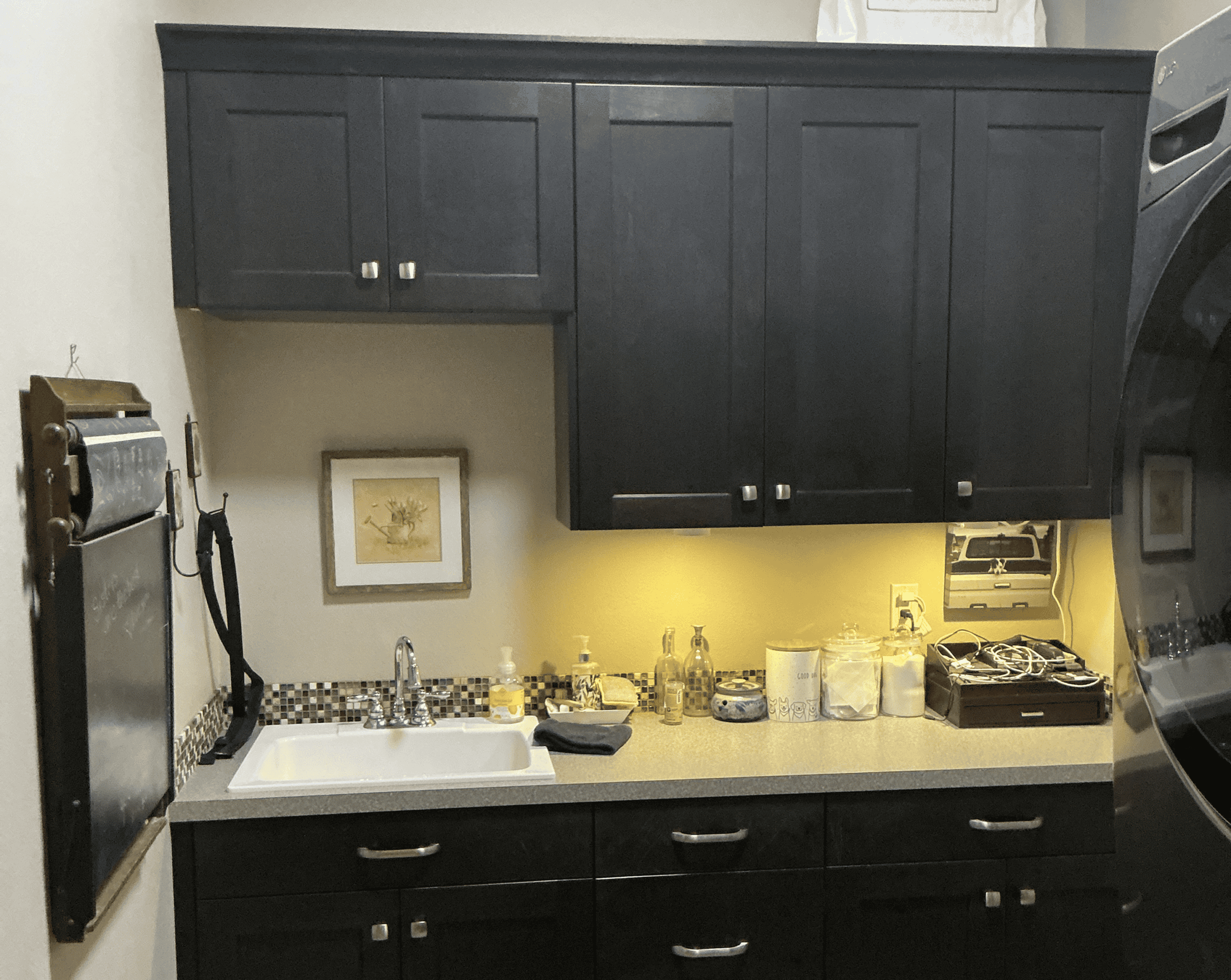 Dark cabinetry with a white sink and various cleaning supplies on the countertop.