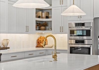 Bright modern kitchen with white cabinets, gold fixtures, and a large island.