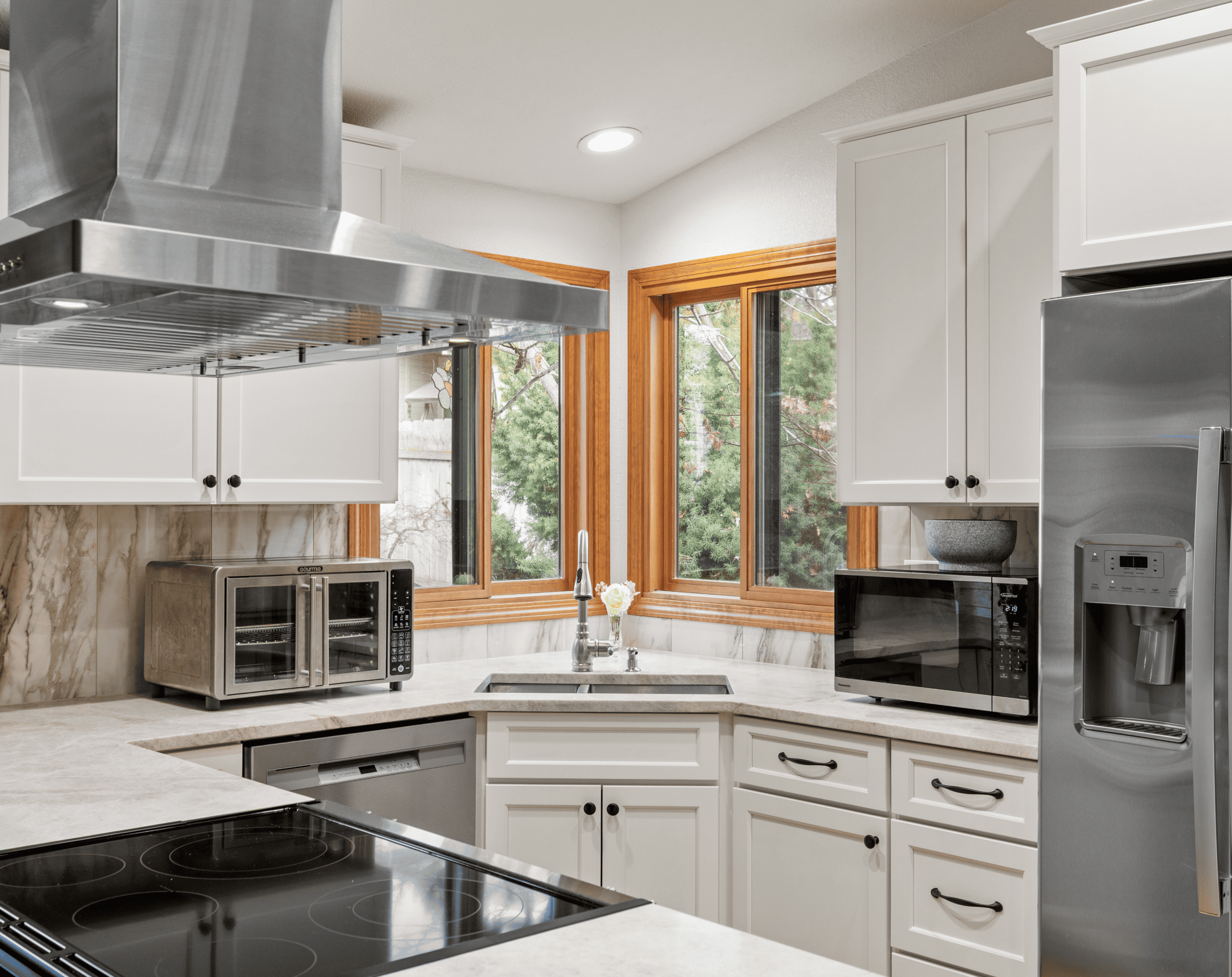 Modern Kitchen Design Bright modern kitchen with white cabinets, stainless steel appliances, and large windows.