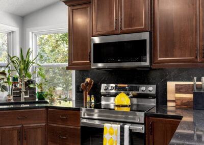 Beautiful kitchen with dark wood cabinets, stainless steel stove, and black granite countertops.